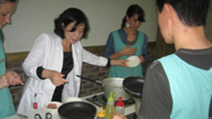 a group of people standing around a table preparing food