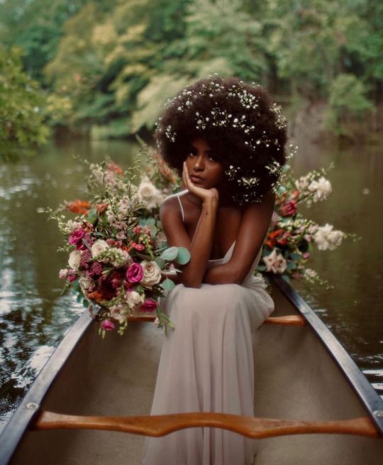 a woman sitting in a boat with flowers on her head