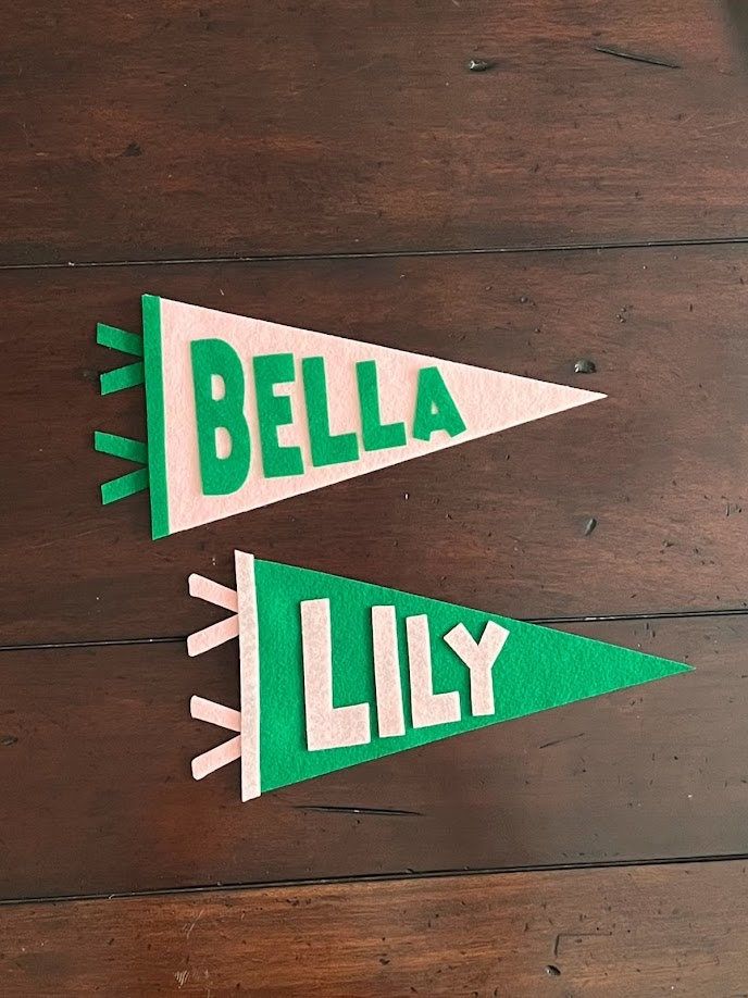 two green and white paper pennants with the words bella lily on them sitting on a wooden surface