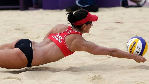 a woman dives to catch a volleyball on the beach