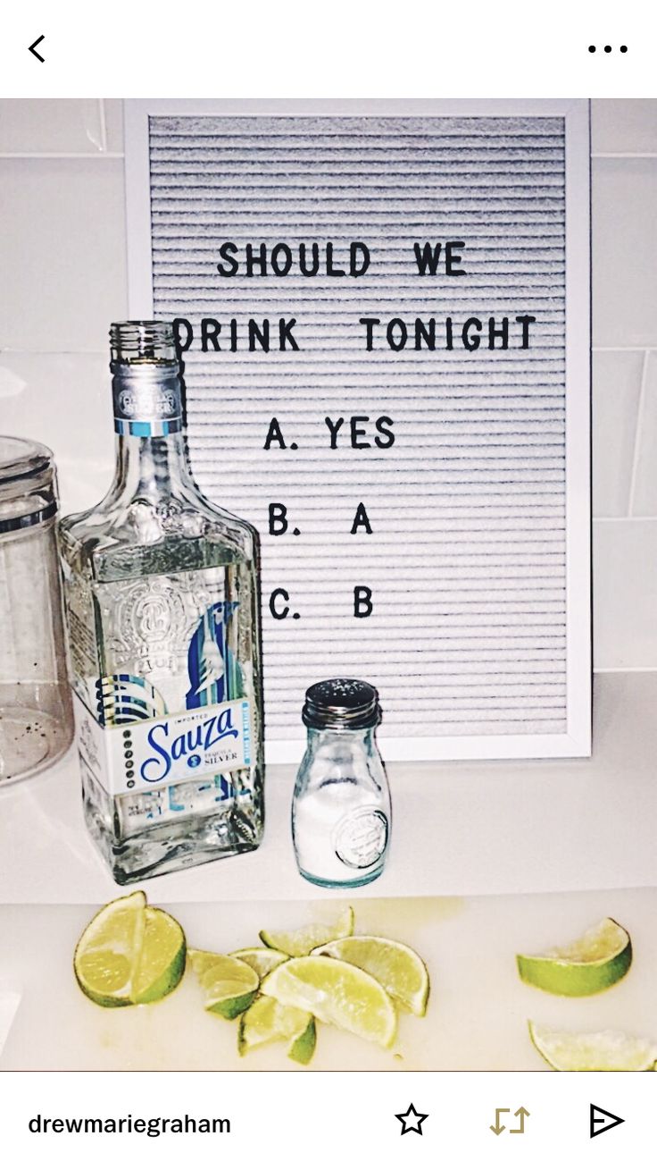 a bottle of vodka sitting on top of a counter next to sliced limes