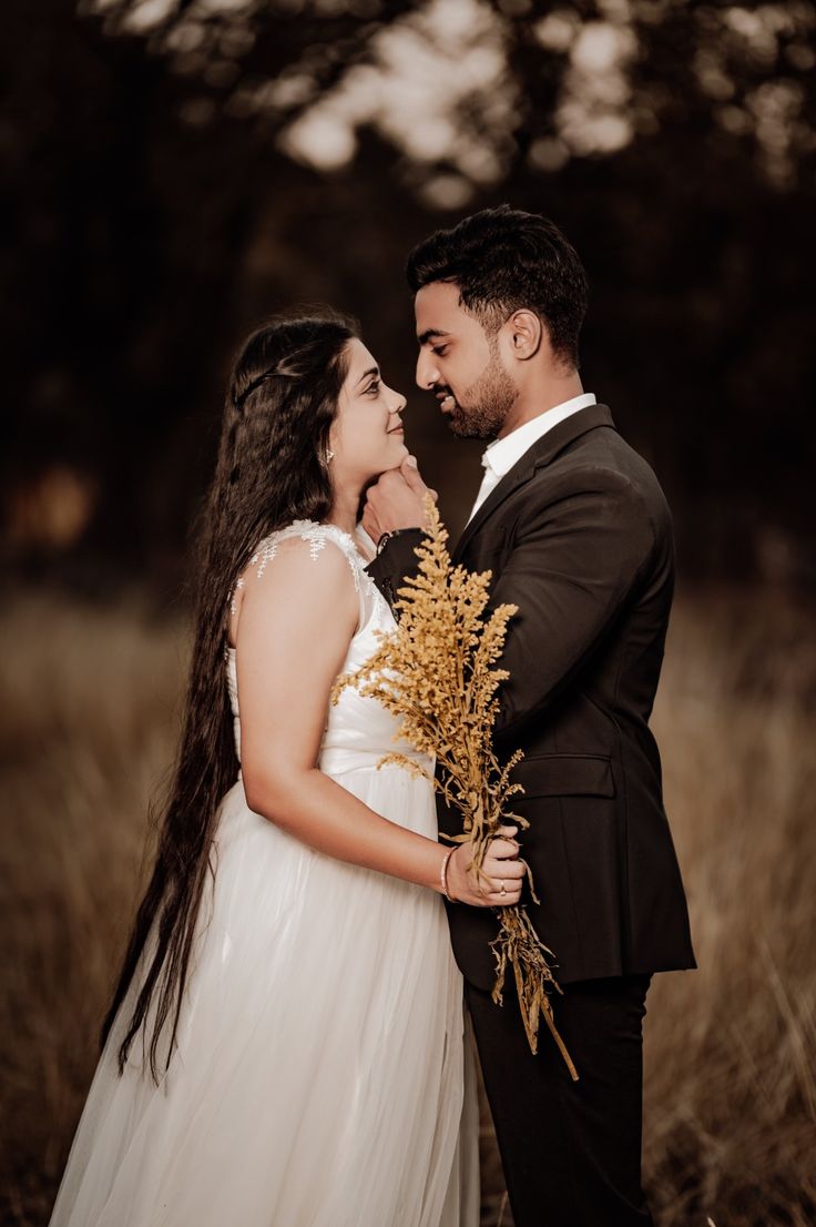 a bride and groom standing together in the grass