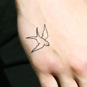 a small bird tattoo on the foot of a person's left foot and hand