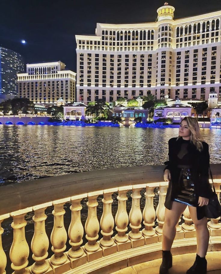 a woman standing in front of the las vegas hotel and casino at night with her hands on her hips