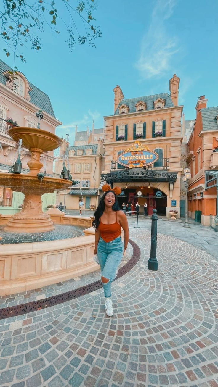 a woman is walking in front of a fountain