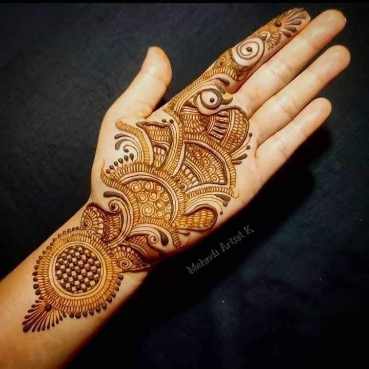 a woman's hand with henna tattoos on it, showing the intricate design