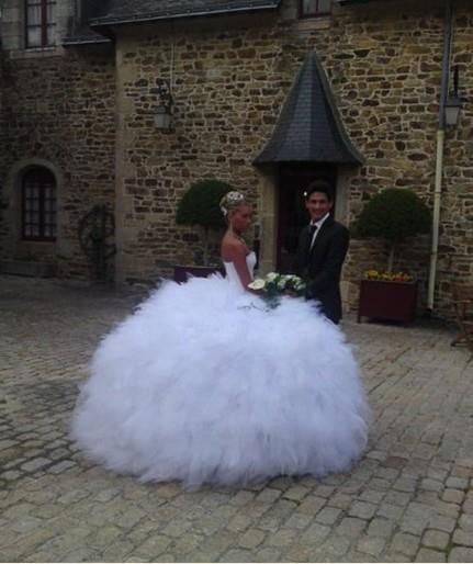 a man and woman standing next to each other in front of a building with a large white ball gown on it