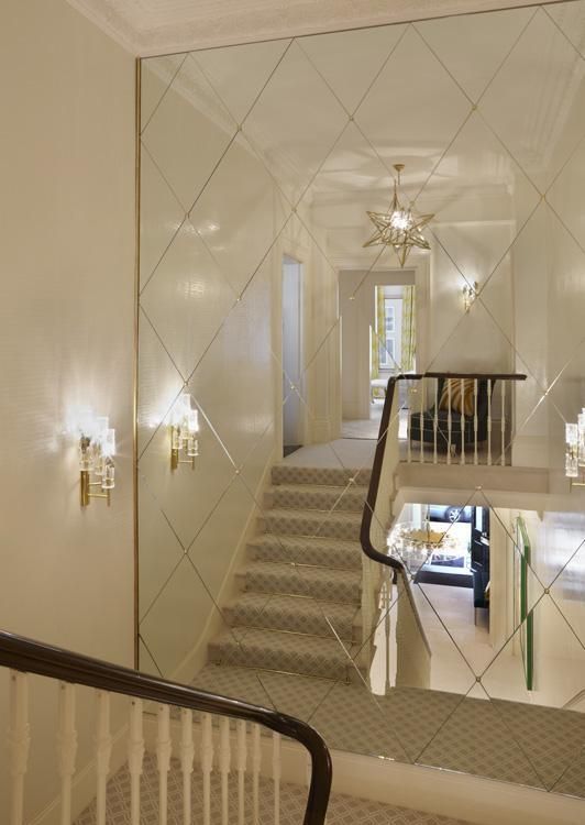 an image of a hallway with stairs and chandelier on the wall in front of it