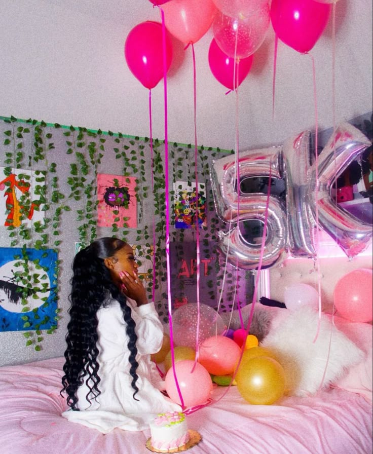 a woman sitting on top of a bed surrounded by balloons