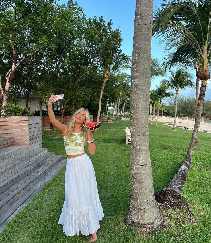 a woman standing next to a palm tree holding a frisbee in her hand