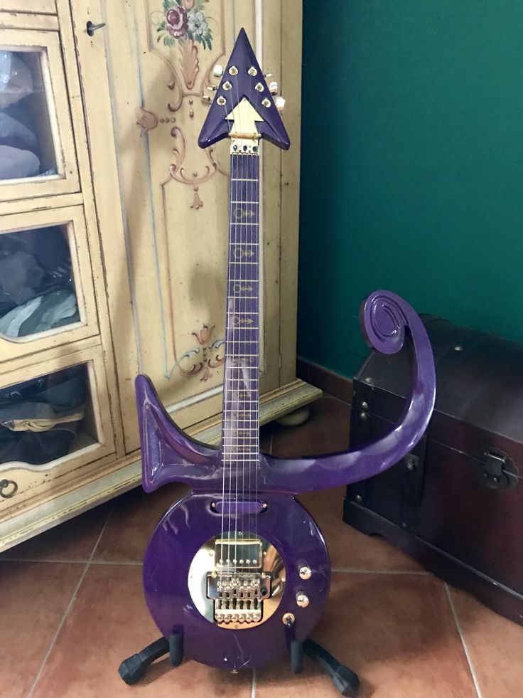 a purple guitar sitting on top of a floor next to a cabinet with drawers in it