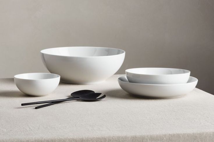 three white bowls and two spoons on a table