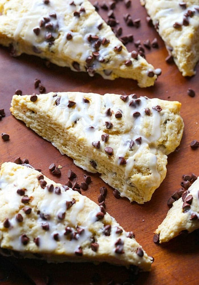 chocolate chip scones with white icing on a cutting board, ready to be eaten