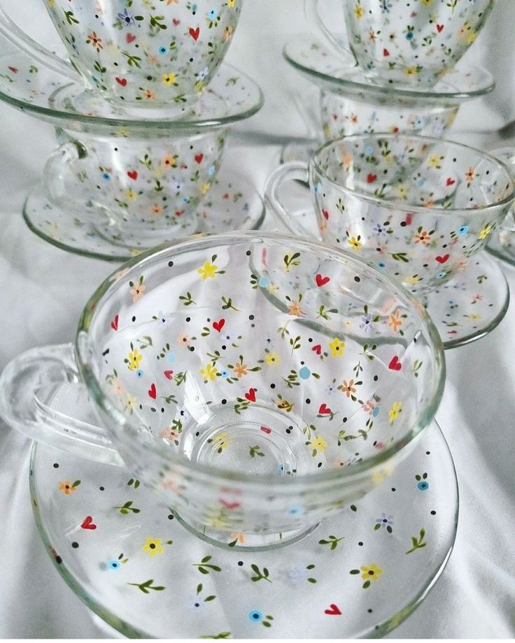 four glass dishes with colorful sprinkles on them are sitting on a white tablecloth