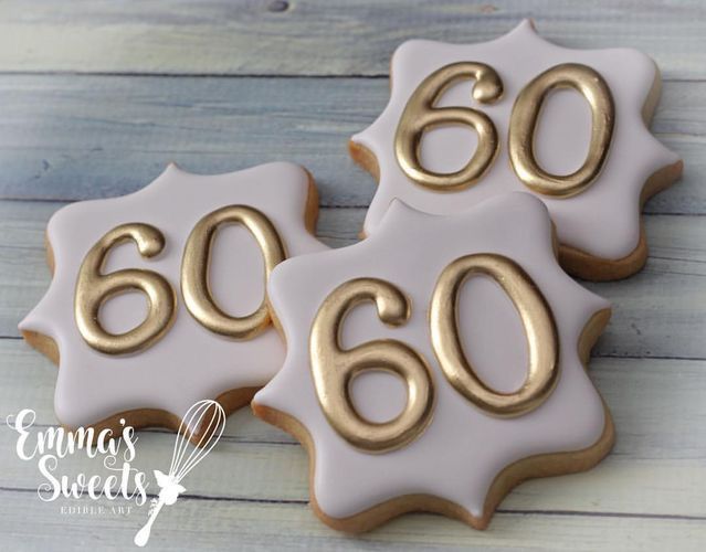 three decorated cookies with the number 60 on them are sitting next to each other in white and gold icing