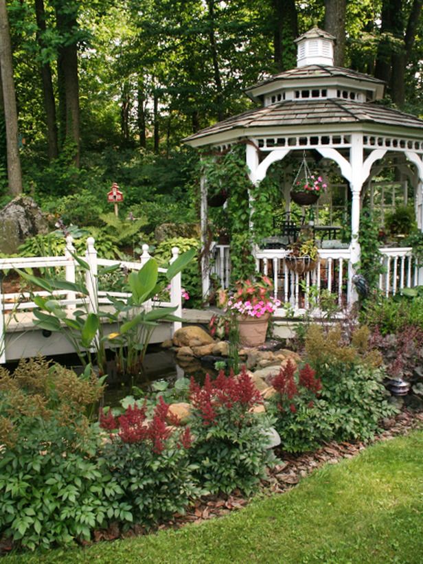 a white gazebo surrounded by lots of flowers and greenery