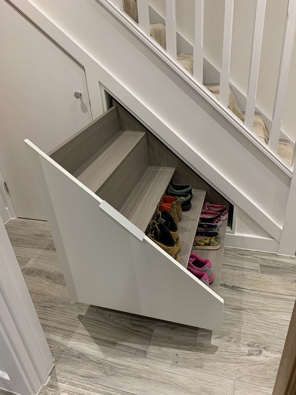 an under the stairs closet with shoes in it