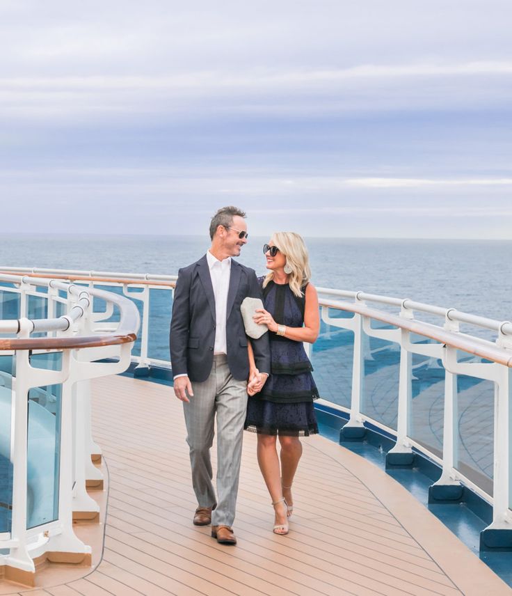 a man and woman are walking on the deck of a cruise ship near the ocean