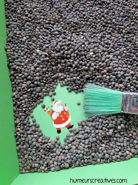 a green brush sitting on top of some black beans in front of a christmas card