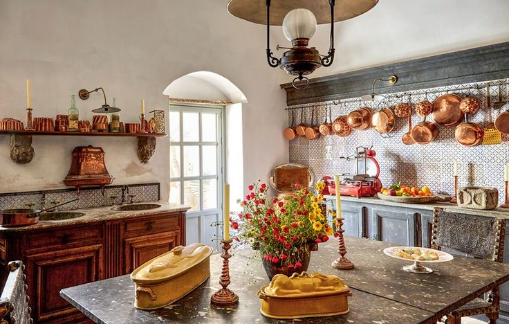 an old fashioned kitchen with pots and pans hanging from the ceiling over the table