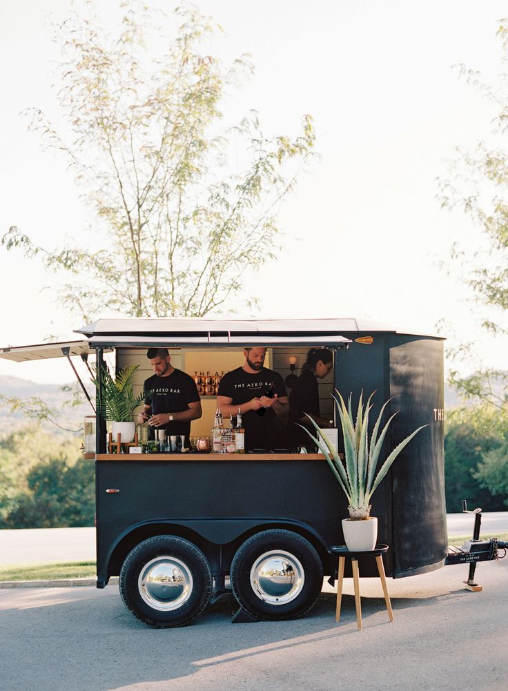 the food truck is parked on the side of the road with two men behind it