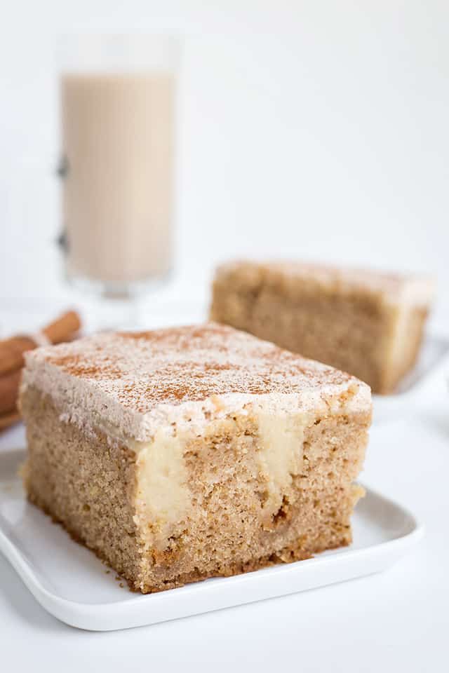 a piece of cake sitting on top of a white plate next to a glass of milk