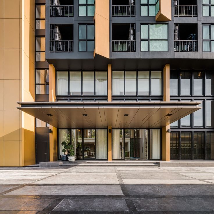 an empty parking lot in front of a tall building with lots of windows and balconies