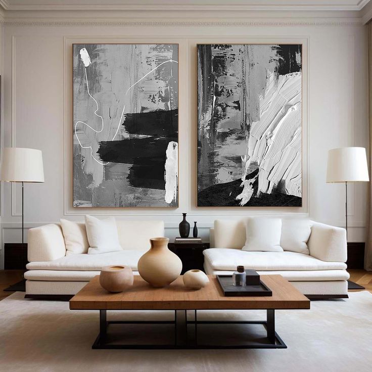 two paintings hang on the wall above a white couch and coffee table in a living room