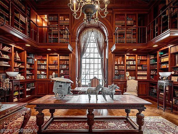 the library has many bookshelves and tables with chairs around it, along with an ornate chandelier