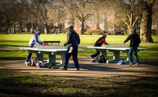 several people playing ping pong in the park