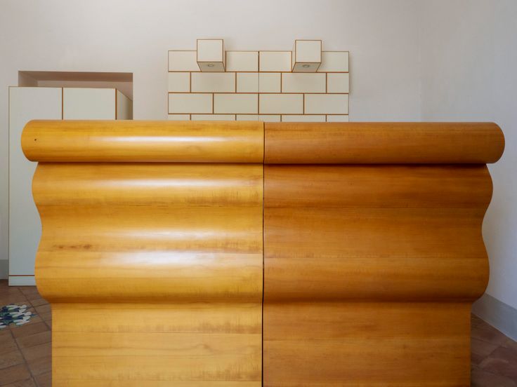 a large wooden cabinet sitting on top of a tiled floor next to a white wall