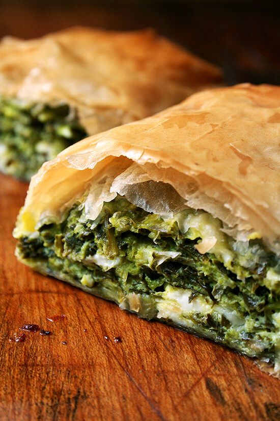 a close up of a pastry on a wooden table with broccoli and cheese