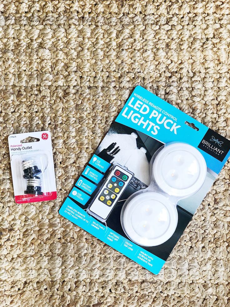 two white lights sitting on top of a carpet next to a package of remote controls