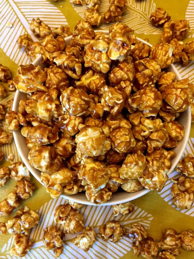 a bowl filled with caramel popcorn on top of a table