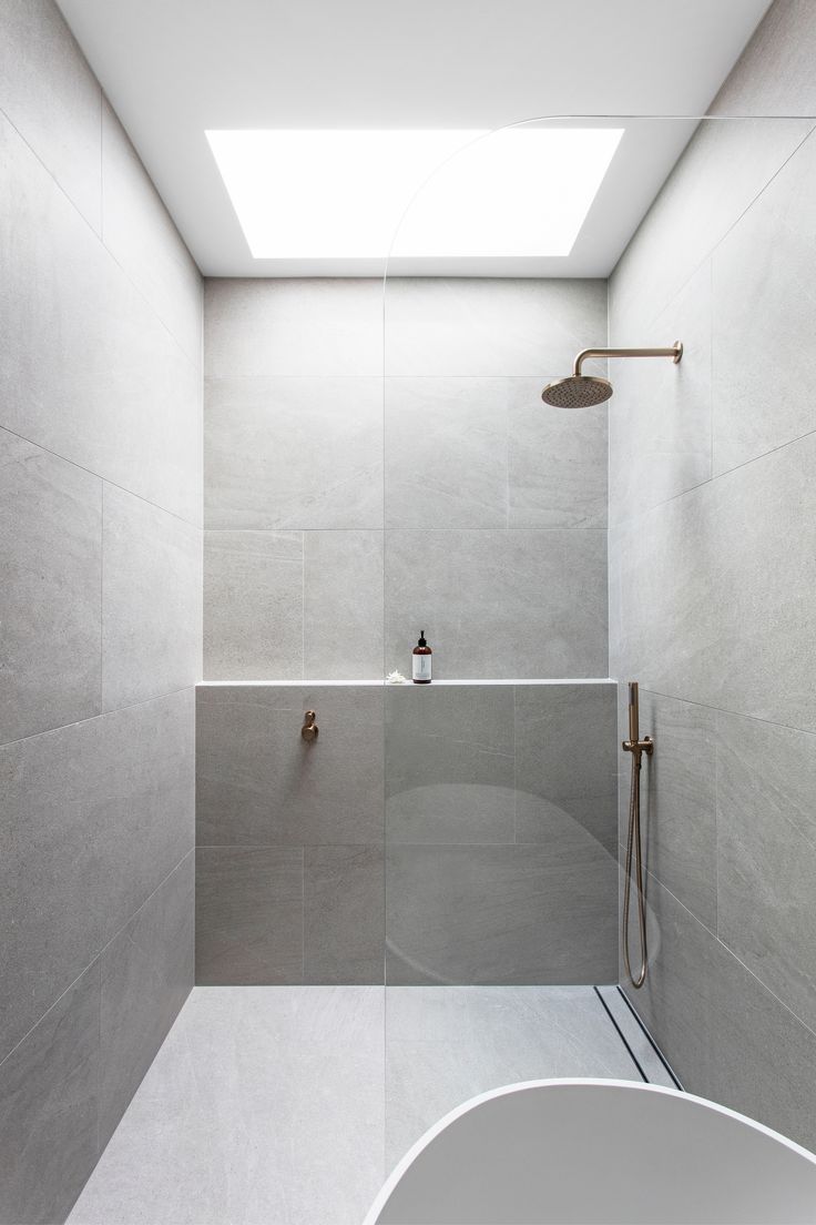 a white bathroom with a skylight above the bathtub and shower head is shown