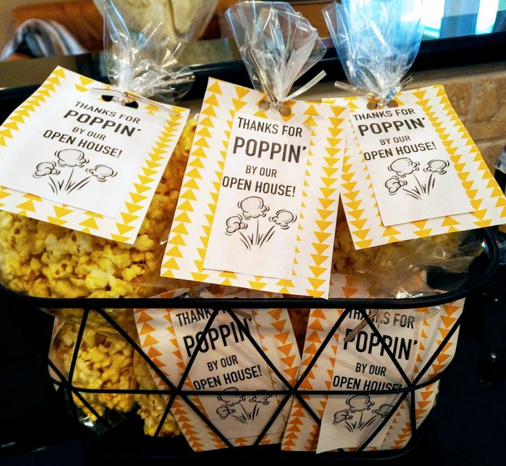 bags of popcorn sitting on top of a table next to plastic bags with tags that say poppin's open house