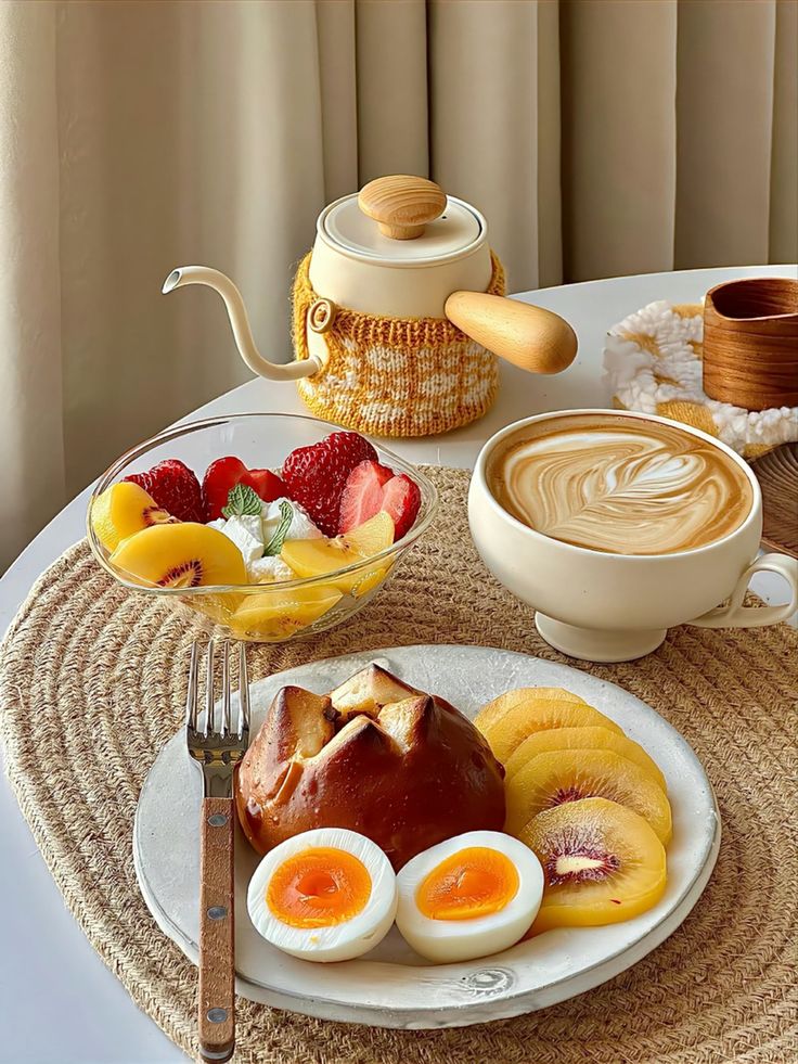 there is a plate with some fruit and eggs on it next to a cup of coffee