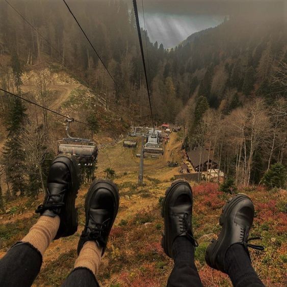 two people standing on a ski lift with their feet in the air