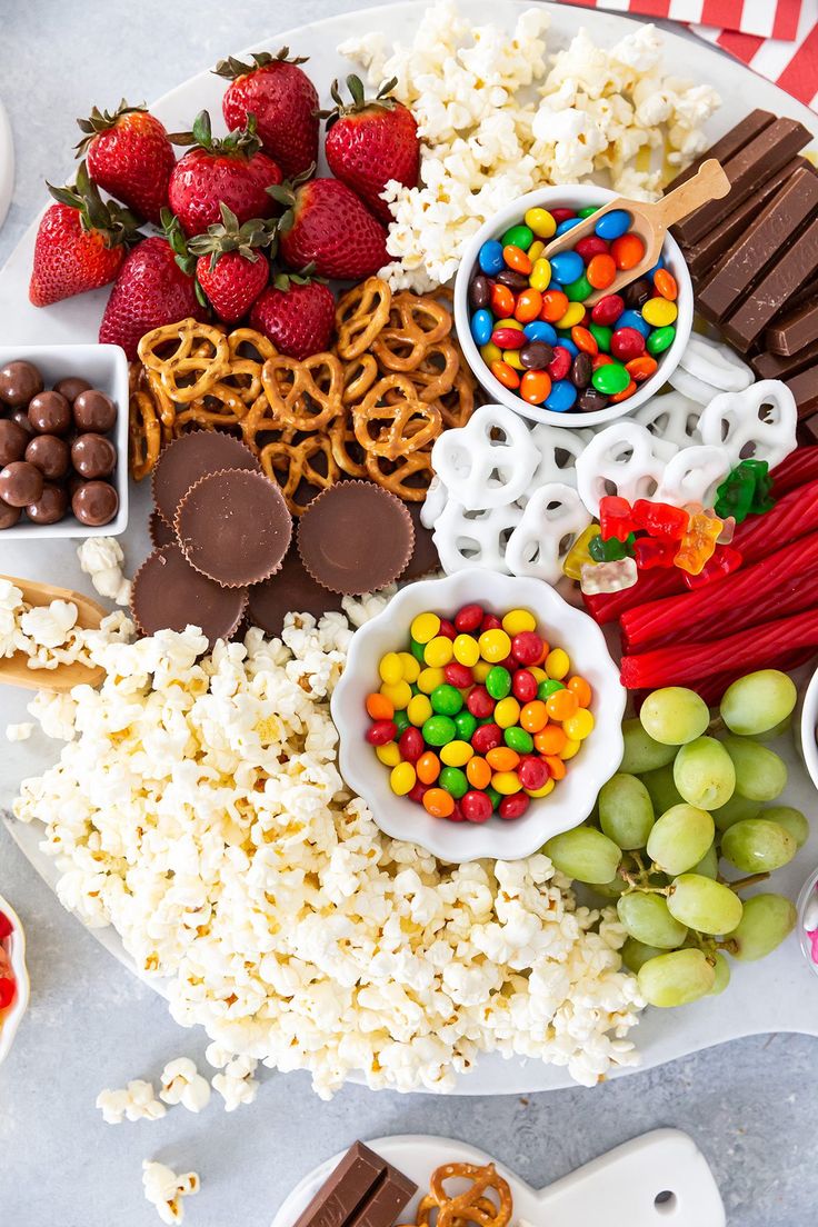 a platter filled with candy, pretzels, strawberries and chocolate