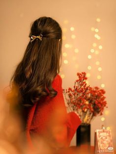 a woman sitting at a table with flowers in front of her and lights behind her