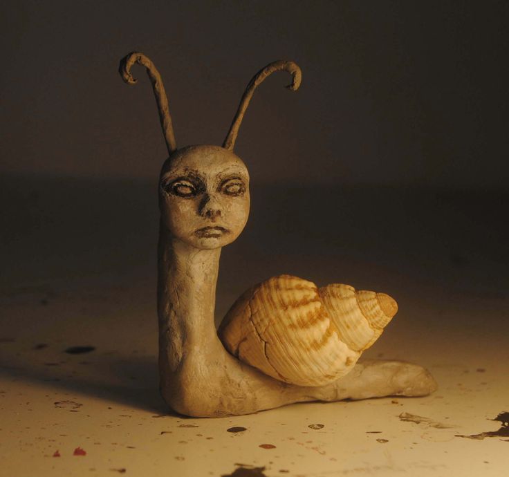 a snail statue sitting on top of a floor next to a shell with its eyes closed