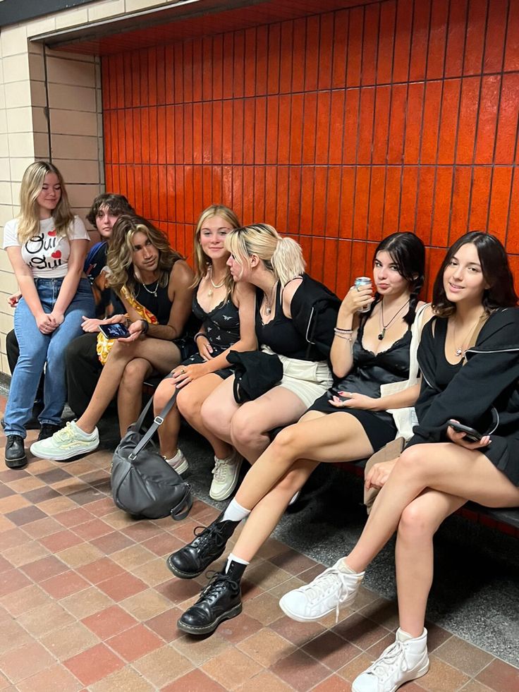 a group of young women sitting next to each other in front of a red wall