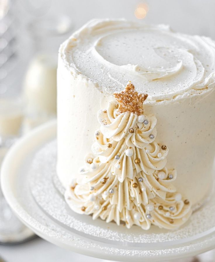 a white frosted cake decorated with a gold christmas tree decoration on top of it