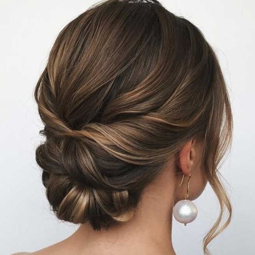 a woman with her hair in a low bun and pearl earrings on her head, looking to the side