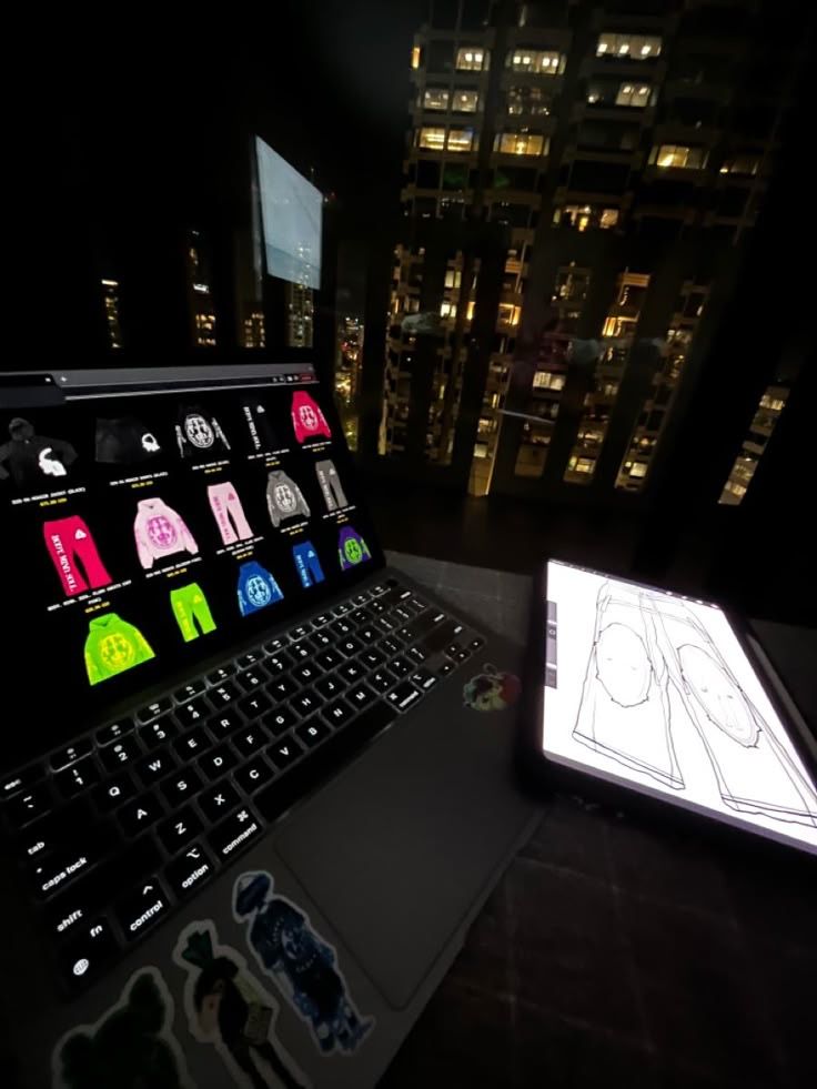 an open laptop computer sitting on top of a desk next to a lit up tablet