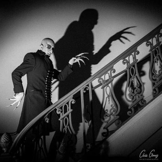 a man in a suit and mask standing on the stairs with his shadow projected over him