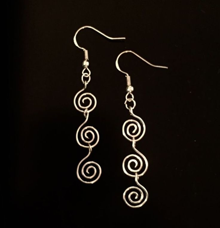 two silver spiral earrings on a black background