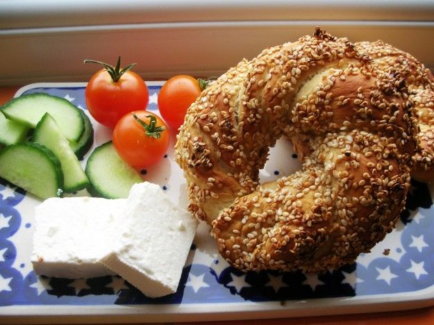 a bagel, cucumber and tomatoes on a blue and white platter