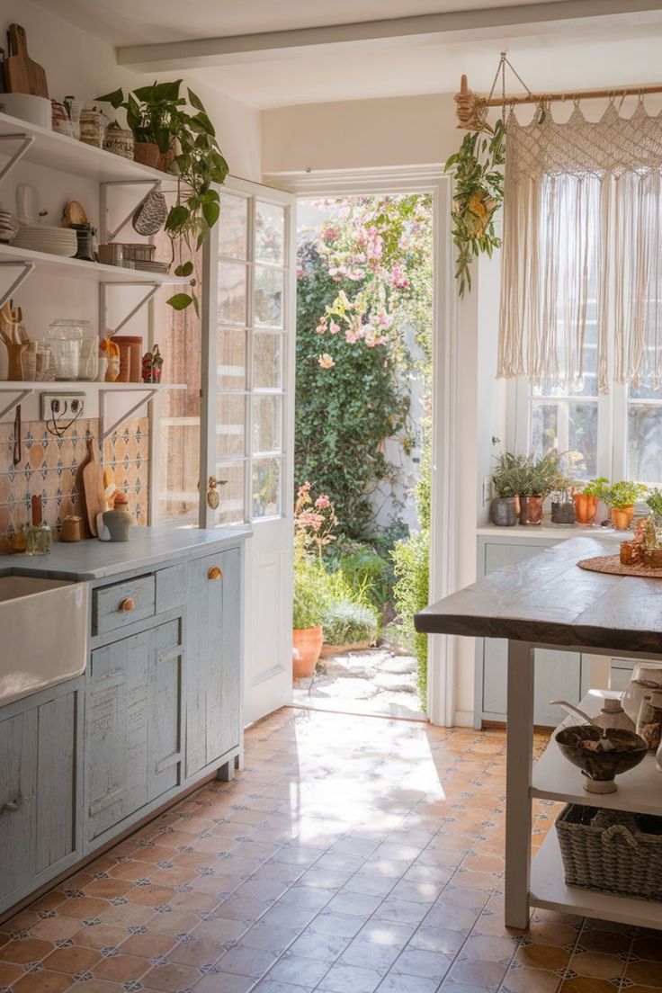 Light-filled vintage kitchen with blue cabinets, open shelving, and a garden view through the open door Rustic Boho Kitchen Vintage, Italian Kitchen Aesthetic, Rustic Boho Kitchen, Blue Cabinetry, Colorful Backsplash, Vintage Inspired Kitchen, Italian Kitchen, Boho Kitchen, Vintage Dressers