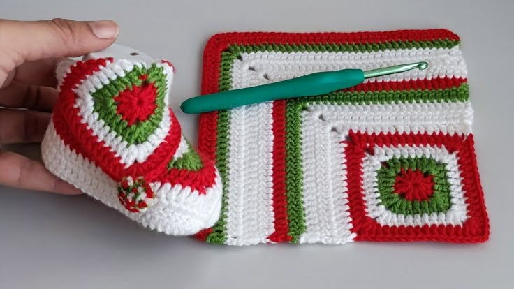 a crocheted christmas stocking with a green handled tool in the center and a white square on top